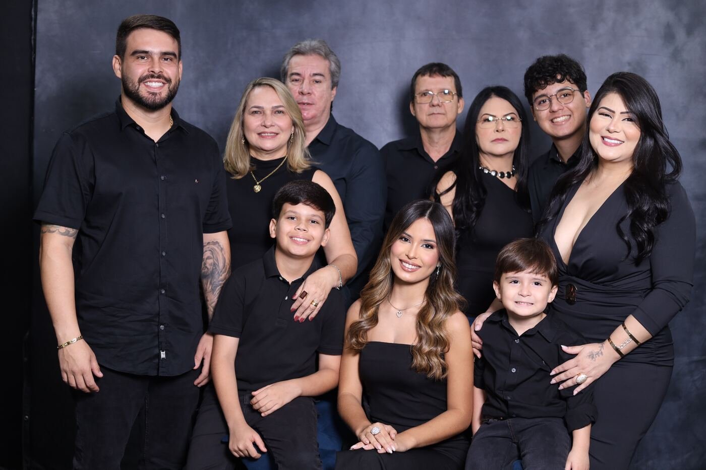 Família grande em roupa social diante de fundo escuro