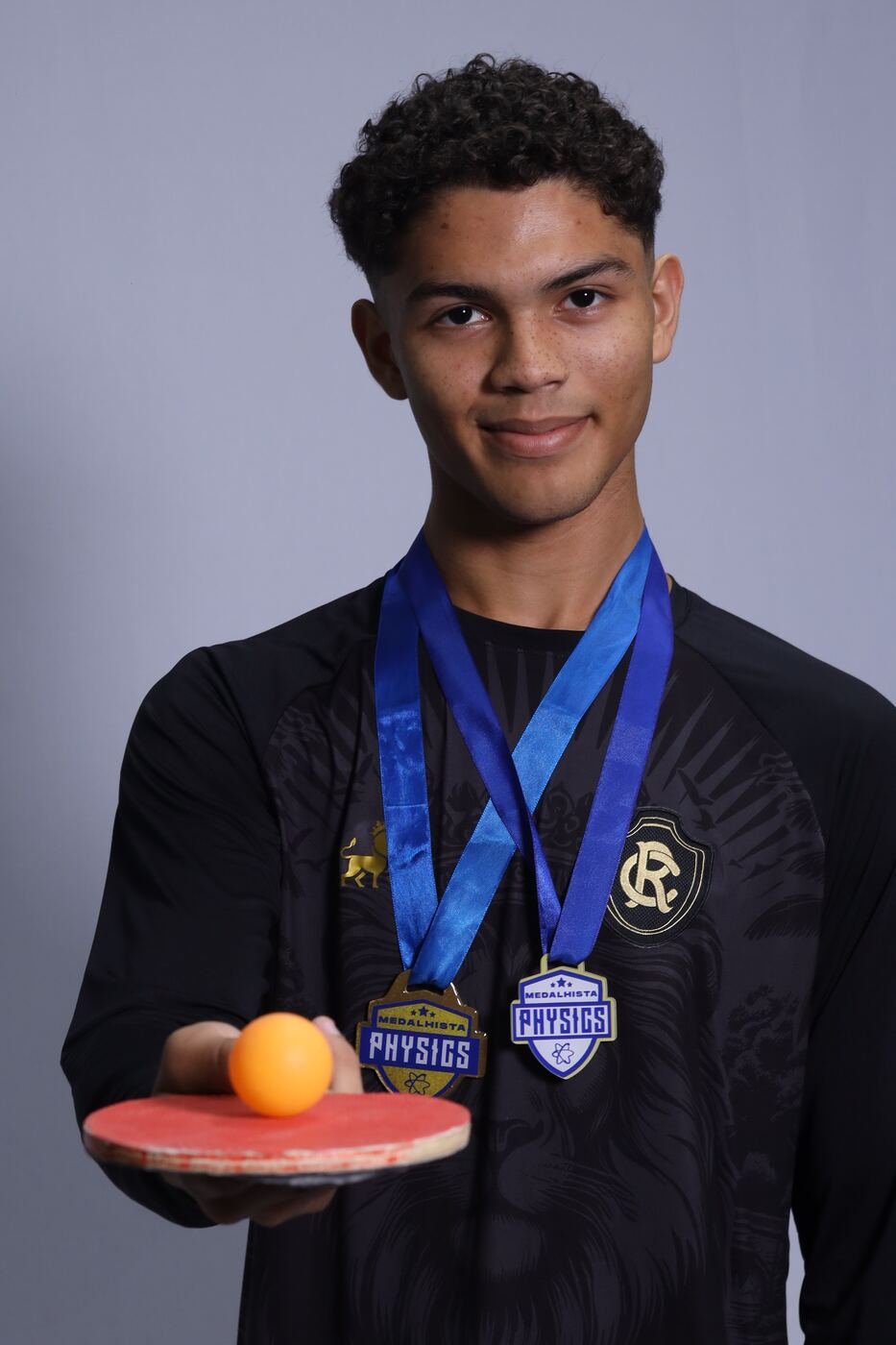 Formando com medalhas no peito e raquete de tênis de mesa