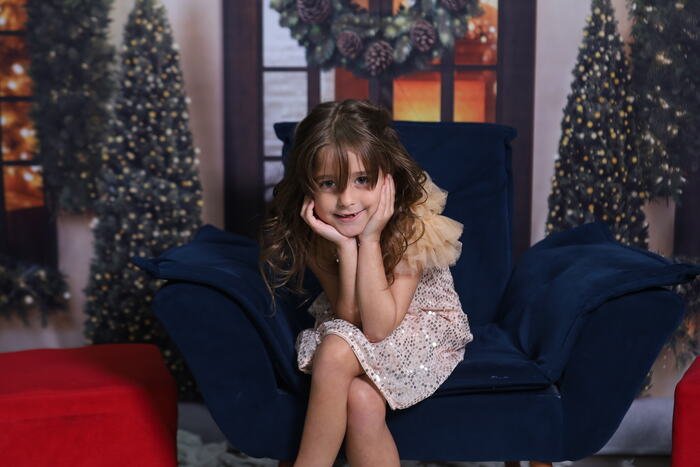 Menina sentada na poltrona azul no cenário de Natal