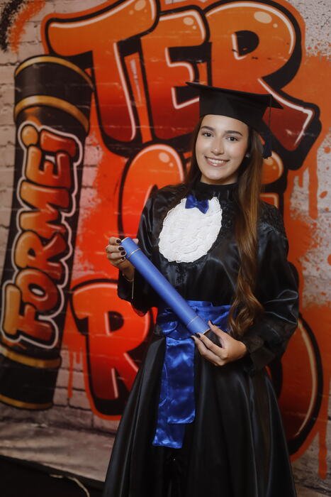 Formanda com o canudo no painel Formei